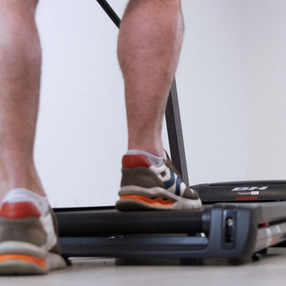 Gros plan sur les pieds d'un utilisateur en marche sur le tapis de course Pioneer G6484H, surface antidérapante