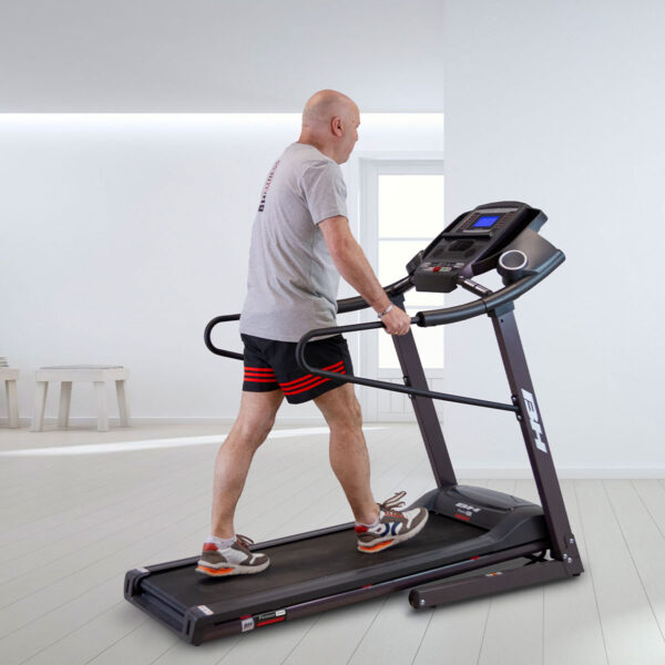 Homme en marche sur le tapis de course Pioneer G6484H, vue latérale avec barres de maintien et console digitale